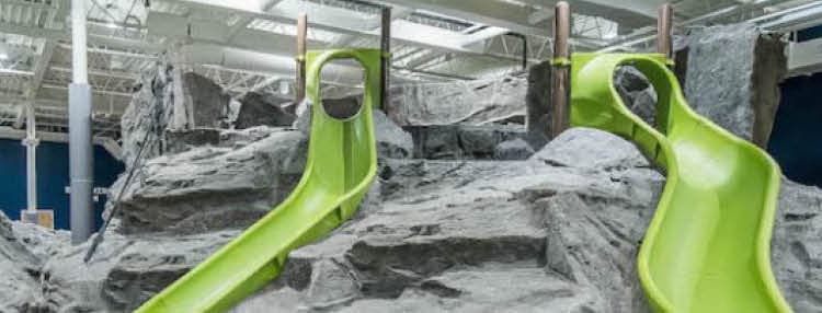 Two large green indoor slides surrounded by rock-like structures.