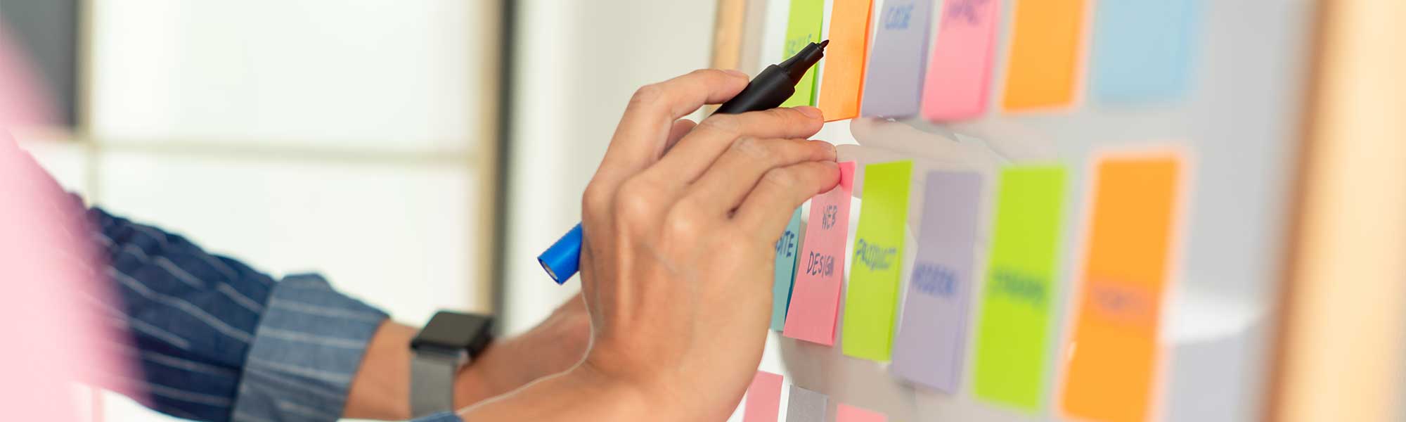 Person writing on a sticky note wall