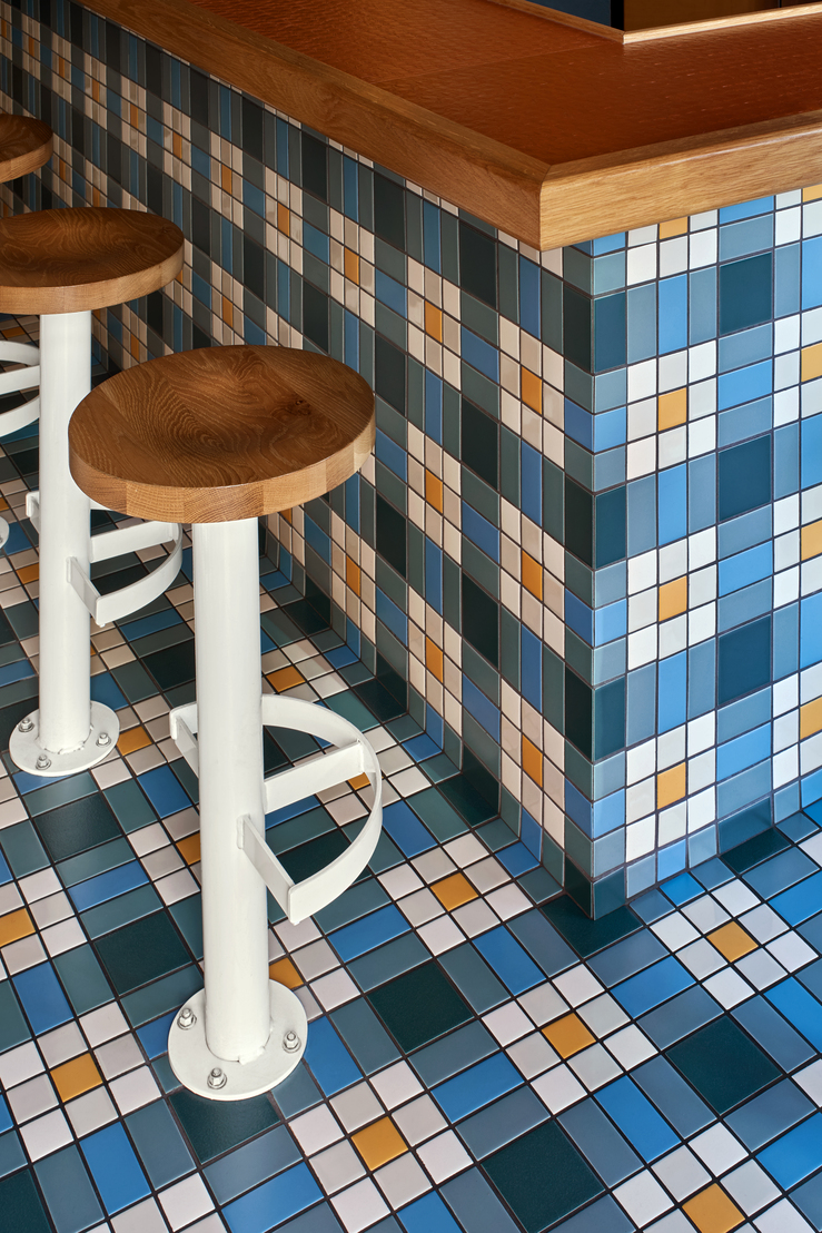 14th Street Bar "Jane Jane" - shot of a circular wodden bar stool ontop of blue, yellow, and white floor tile