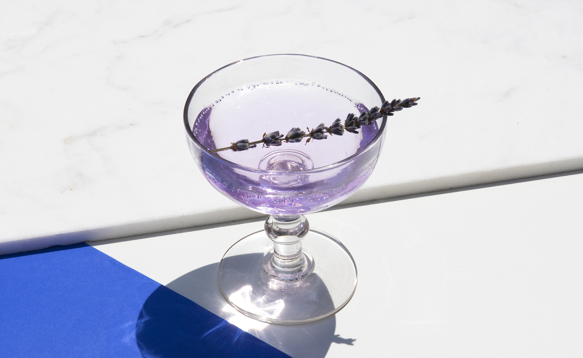 purple cocktail in stem glass with garnish
