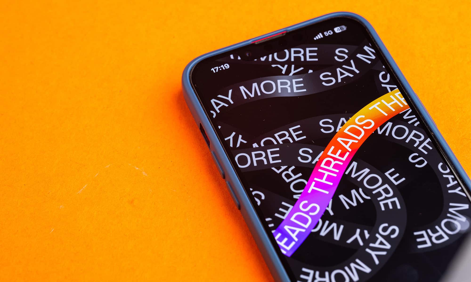 a phone with threads on it on orange background